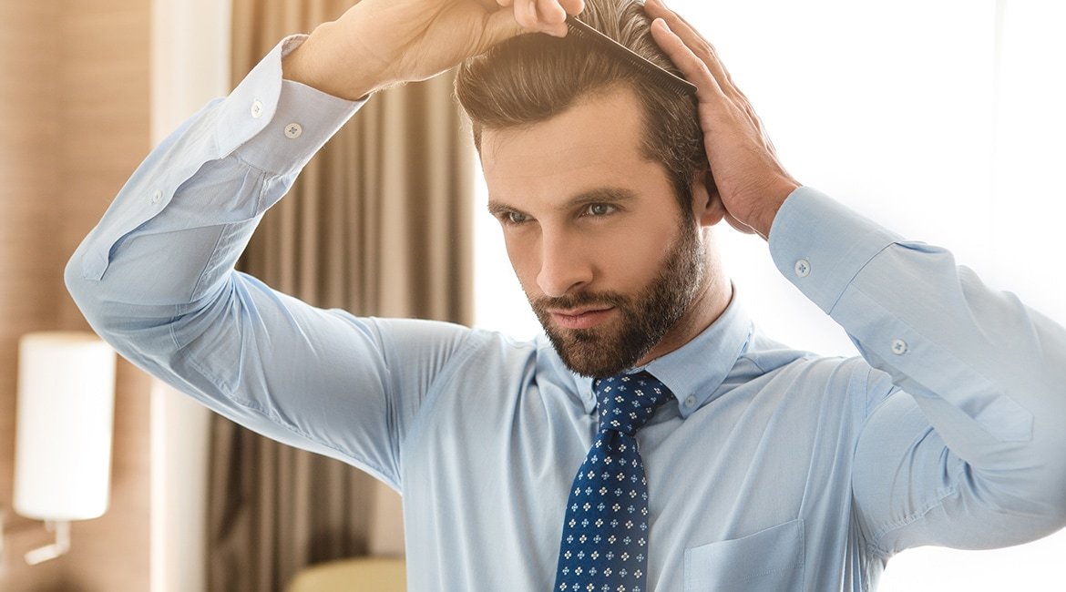 Ein junger Mann kämmt sein Haar.